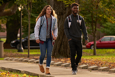 Two students walking acros campus.