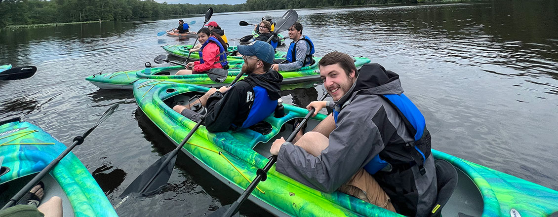 students and faculty on the lake in kayaks