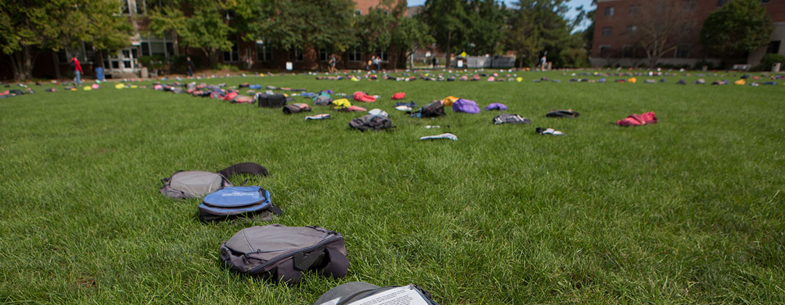 Backpacks arranged on the grass for a "Send Silence Packing" event
