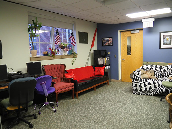 The Veterans Center room showing two couches, several chairs, and American flags
